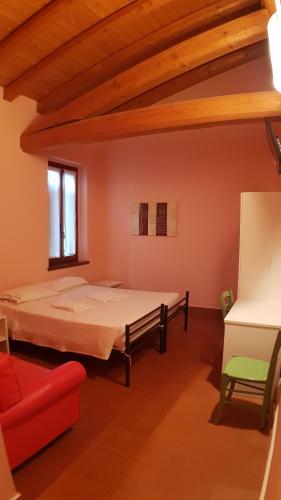 1 dormitorio con 1 cama y 1 silla roja en Ostello Molino Di Basso en Roccafranca