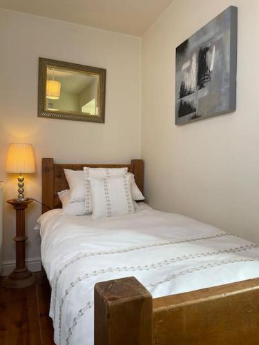 a bedroom with a large white bed with a mirror at Daisy Cottage in Keighley