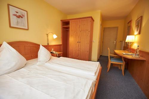a bedroom with a large white bed and a desk at Gasthof-Hotel Zur Post Samerberg in Törwang