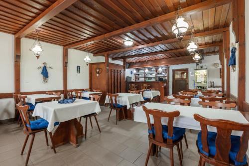 a restaurant with white tables and chairs and wooden ceilings at Penzion POSADA in Podivín