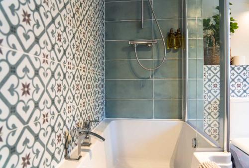 a bathroom with a tub and a shower with blue tiles at Harbour House in Portree