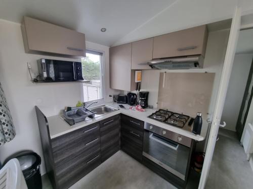 une petite cuisine avec un évier et une cuisinière dans l'établissement Joli mobil home 4-6 personnes 416, à Saint-Jean-de-Monts