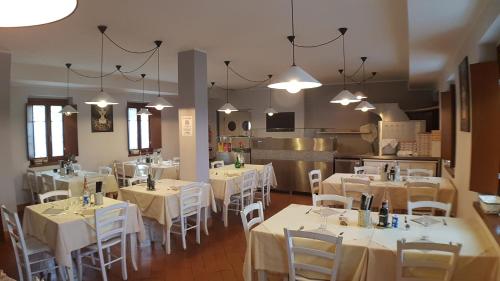 un comedor con mesas blancas y sillas blancas en Ostello Molino Di Basso, en Roccafranca