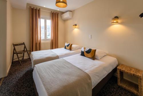 um quarto de hotel com duas camas e uma janela em L'Aptois Hôtel em Apt