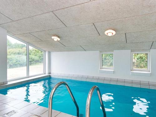 uma piscina com água azul num quarto com janelas em 10 person holiday home in Ebeltoft em Ebeltoft