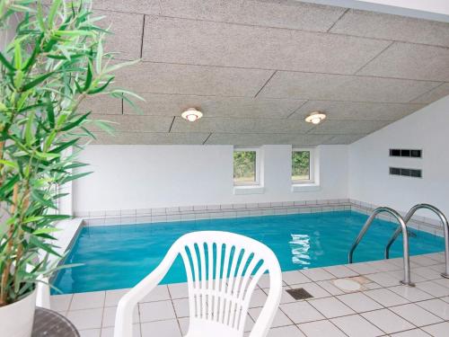 uma cadeira branca sentada em frente a uma piscina em 10 person holiday home in Ebeltoft em Ebeltoft