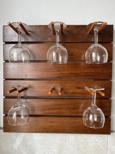 four wine glasses hanging on a wooden wall at Cosy Seaview in Pointe aux Sable