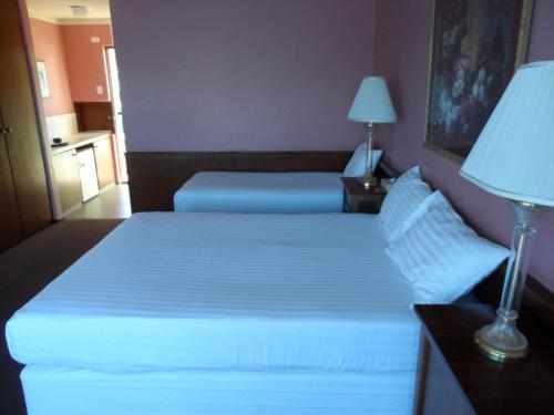 a hotel room with two beds and a lamp at Clifton Motel & Grittleton Lodge in Bunbury