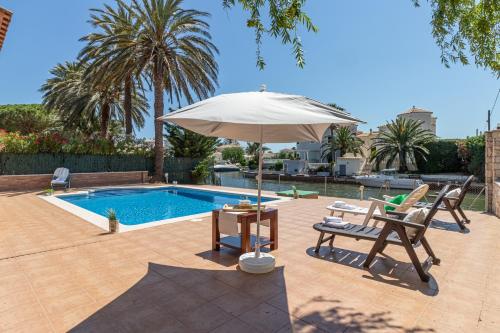 a patio with an umbrella and chairs next to a pool at Apart-rent Villa Pani 0145 in Empuriabrava
