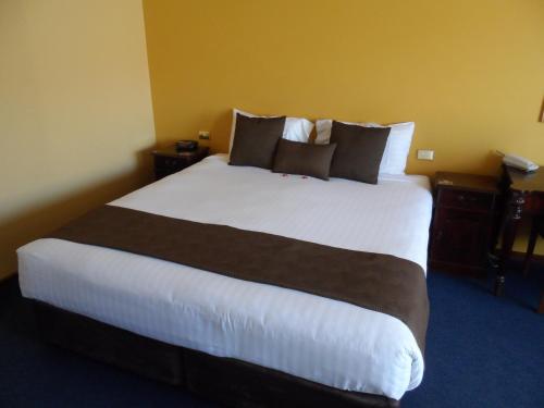 a hotel room with a large white bed with pillows at Clifton Motel & Grittleton Lodge in Bunbury