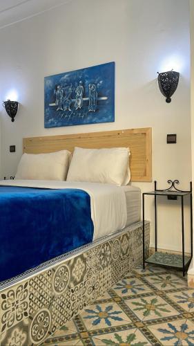a bedroom with a large bed with a painting on the wall at Riad chez brahim in Essaouira