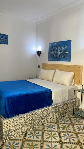 a bedroom with a large bed with a blue blanket at Riad chez brahim in Essaouira