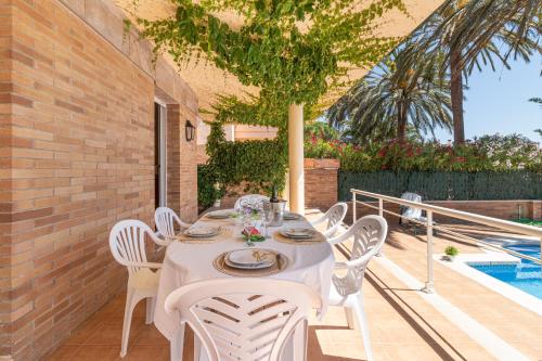 エンプリアブラバにあるApart-rent Villa Pani 0145の白いテーブルと椅子、プール付きのパティオ