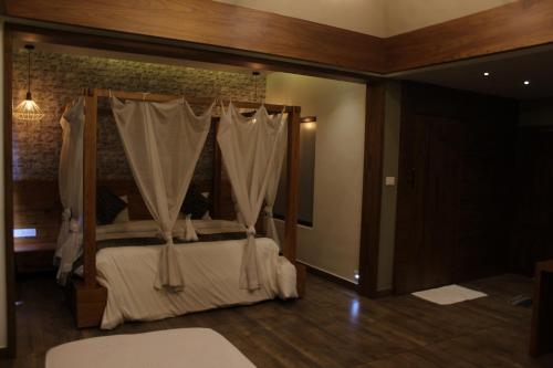 a bedroom with a canopy bed with white curtains at The Wild Trails Clarks Exotica , Munnar in Munnar