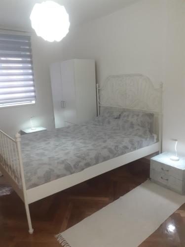 1 cama blanca en una habitación con 2 lámparas en Apartman Jovana en Sremska Mitrovica