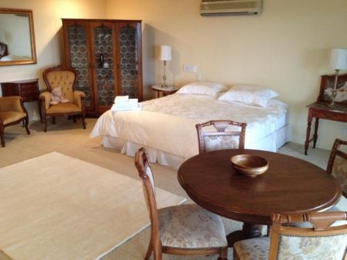 een slaapkamer met een bed en een tafel en stoelen bij Highwood Park B&B Guest Lodge in Maleny