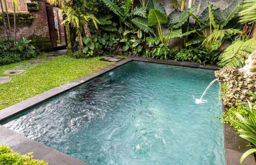 una piscina nel mezzo di un giardino di Tano Home Villas ad Ubud