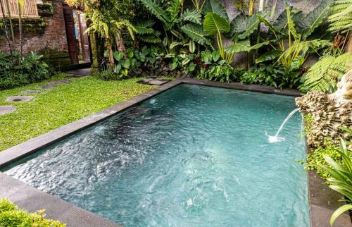 a swimming pool in the middle of a garden at Tano Home Villas in Ubud