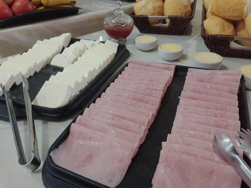 a table with two trays of different types of food at Novo Hotel Três Lagoas in Três Lagoas