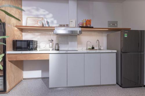 a kitchen with white cabinets and a black refrigerator at M Village Living Võ Thị Sáu in Ho Chi Minh City