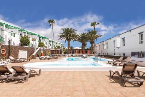 una piscina con tumbonas y un complejo en Naia House Lanzarote, en Puerto del Carmen