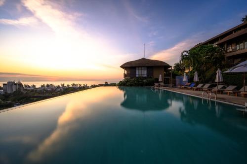 a swimming pool with the sunset in the background at Karon Phunaka Resort in Karon Beach