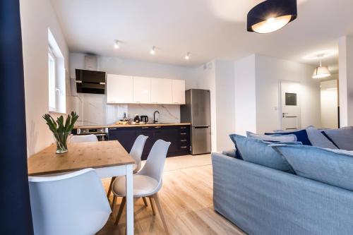 a living room and kitchen with a blue couch and a table at Baltica Towers by Symphony Aparthotels in Gdańsk