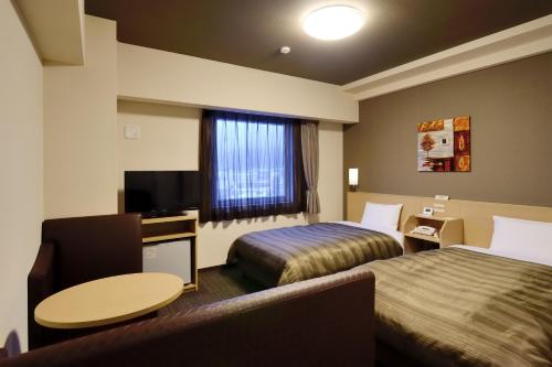 Habitación de hotel con 2 camas y mesa en Hotel Route Inn Ishinomaki Chuo, en Ishinomaki