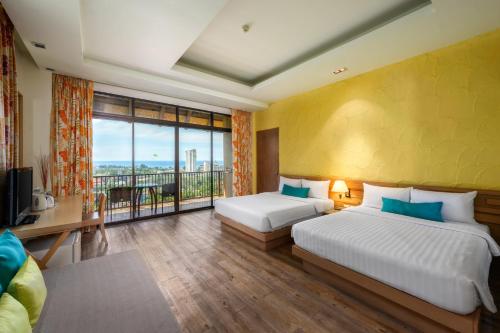 Karon Phunaka Resort في شاطئ كارون: غرفة فندقية بسريرين ونافذة كبيرة