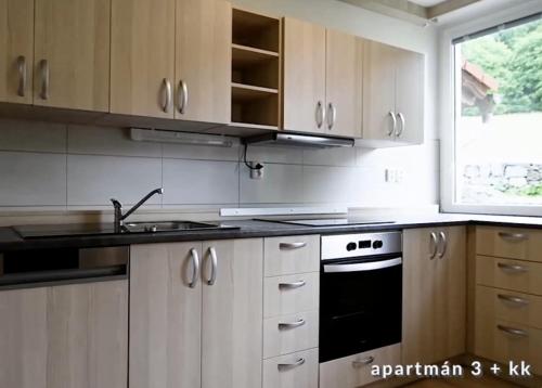a kitchen with white cabinets and a stove and a window at Selský Dvůr Perštejn in Pürstein