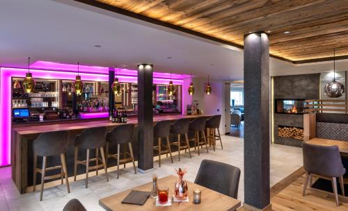 un bar in un ristorante con illuminazione viola di Hotel Wiesnerhof a Vipiteno