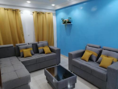 a living room with a gray couch and yellow pillows at Rufisque Dakar in Mbaw
