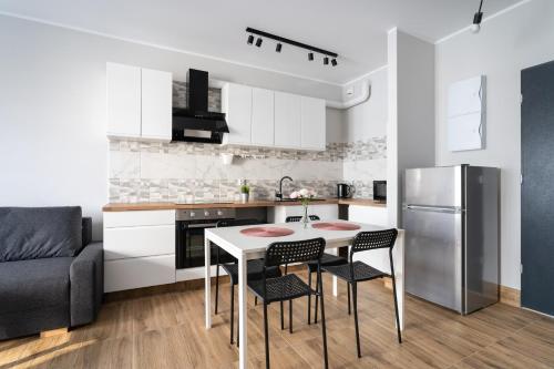 a kitchen with a table and chairs and a refrigerator at Baltica Towers by Symphony Aparthotels in Gdańsk