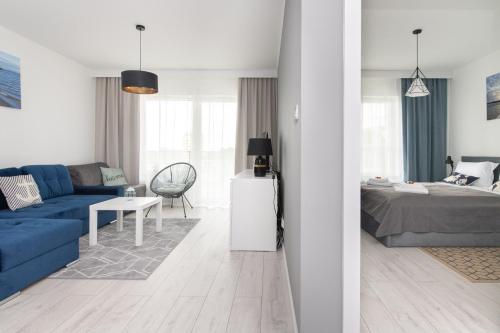 a living room with a blue couch and a bedroom at Baltica Towers by Symphony Aparthotels in Gdańsk