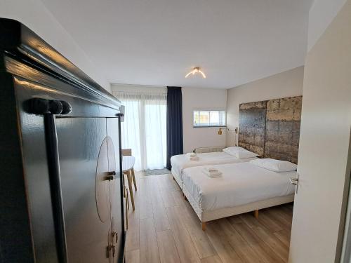 a bedroom with a bed and a refrigerator in it at Seehotel Oostkapelle in Oostkapelle