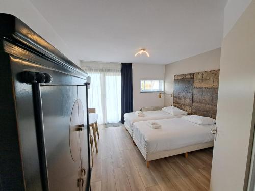 ein Schlafzimmer mit einem Bett und einem Kühlschrank. in der Unterkunft Seehotel Oostkapelle in Oostkapelle