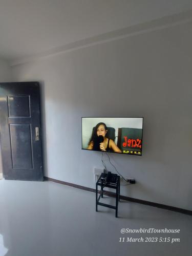 a tv in a white wall with a woman on it at Snowbird Townhouse Azumi in Dumaguete