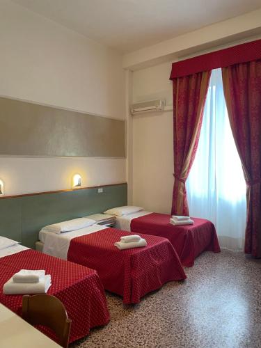ヴィアレッジョにあるHotel Lukasの赤いカーテンが備わるドミトリールームのベッド2台分です。