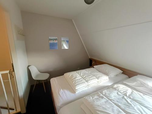 een kleine kamer met 2 bedden en een stoel bij Amelander Kaap 39 in Hollum