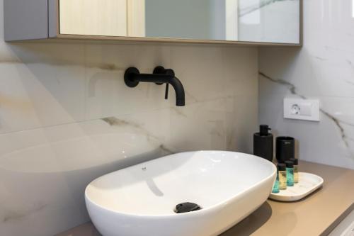 a bathroom with a white sink and a mirror at Orama Luxury Apartments in Nea Kydonia