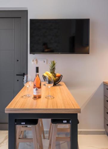 a wooden table with two wine glasses and a bowl of fruit at Orama Luxury Apartments in Nea Kydonia