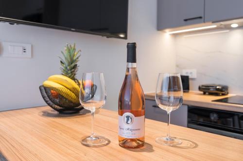 a bottle of wine and two wine glasses on a counter at Orama Luxury Apartments in Nea Kydonia