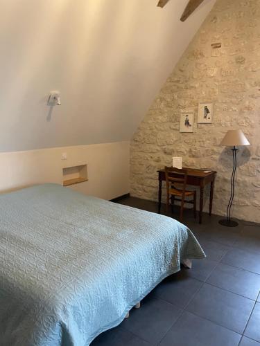 a bedroom with a bed and a table with a lamp at L'Ancien Couvent Cahuzac in Cahuzac