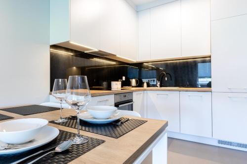 a kitchen with white cabinets and a table with wine glasses at Baltica Towers by Symphony Aparthotels in Gdańsk