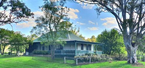 a house with a green roof and a tree at Old Schoolmaster's Cottage on the Barrington River in Barrington