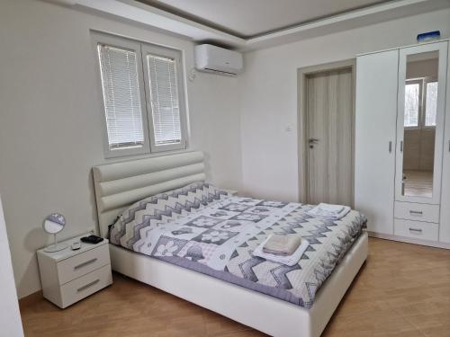 a white bedroom with a bed and a window at Apartman Tološi in Podgorica