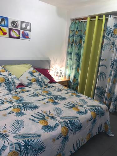 Schlafzimmer mit einem Bett mit einer blauen und weißen Bettdecke in der Unterkunft Bas de villa cosy in Le Lamentin