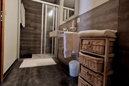 La salle de bains est pourvue d'une douche, d'un lavabo et de serviettes. dans l'établissement Superbe appartement Champex-Lac avec piscine et sauna, à Champex-Lac