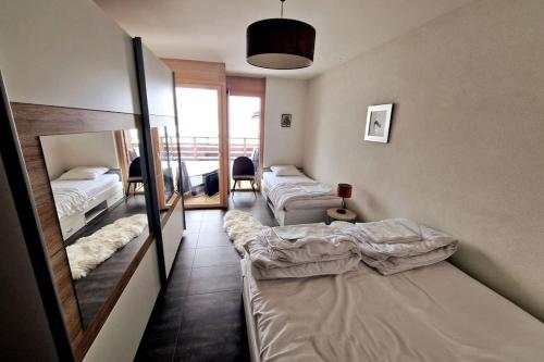 Habitación con 3 camas y espejo. en Superbe appartement Champex-Lac avec piscine et sauna, en Champex