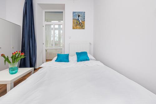 ein Schlafzimmer mit einem großen weißen Bett mit blauen Kissen in der Unterkunft Apartament Mona Lisa Sopot in Sopot